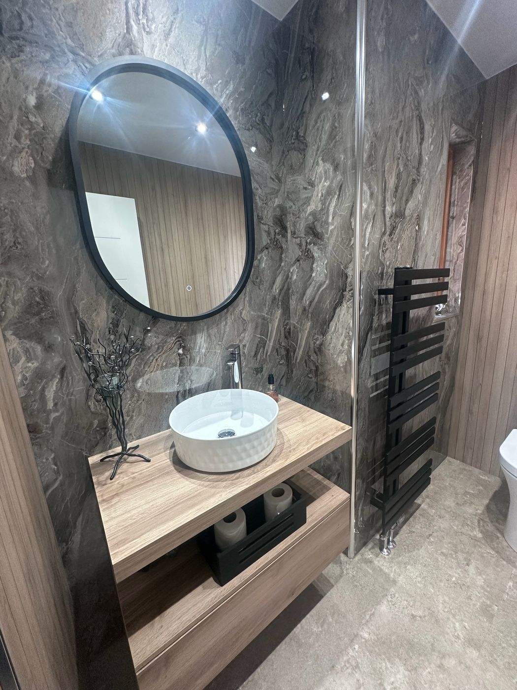 Close-up of marble tiling and oak bathroom joinery