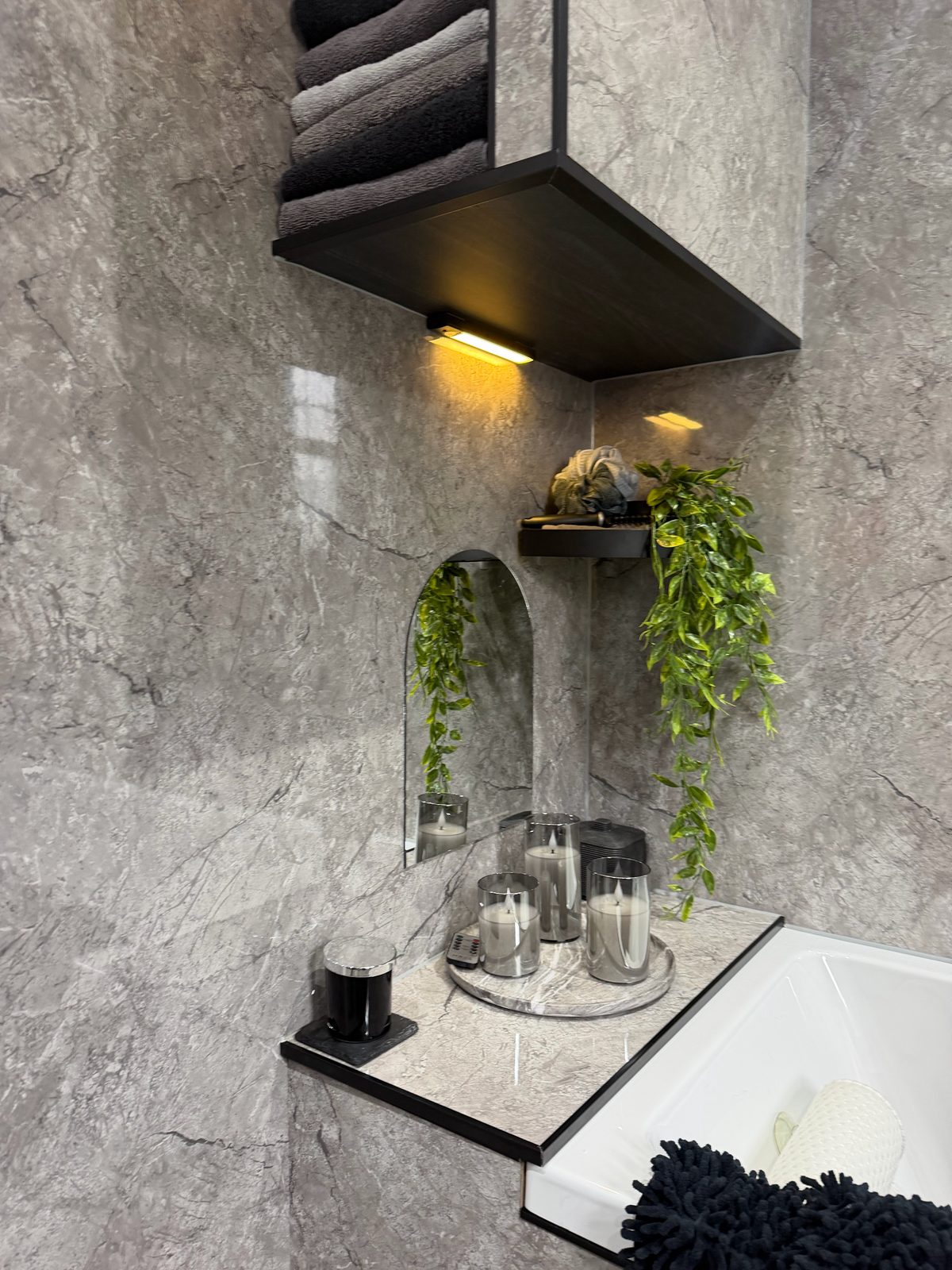 Marble bathroom freestanding bath corner with lit shelf, candles and arched mirror