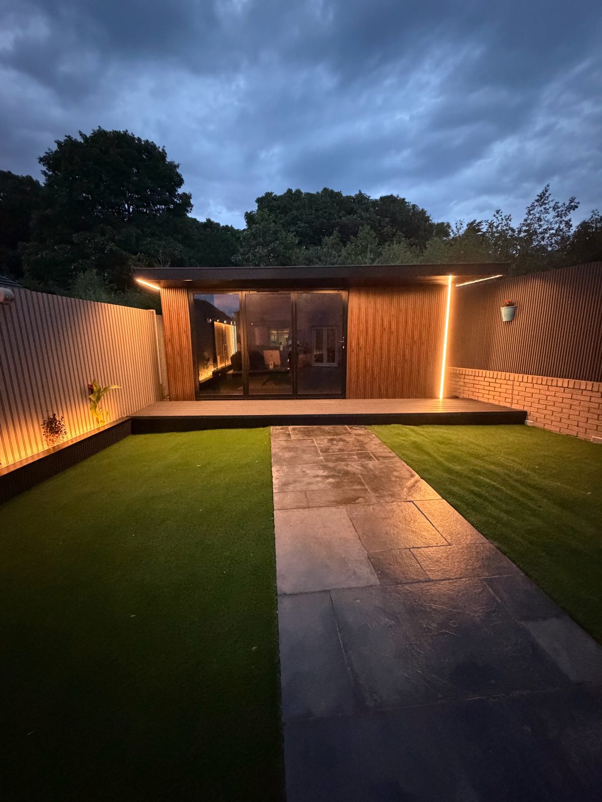 Contemporary garden room with glass doors and stone path at blue hour