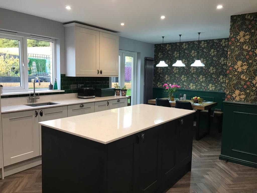 Open-plan kitchen and dining with green paneling and floral wallpaper