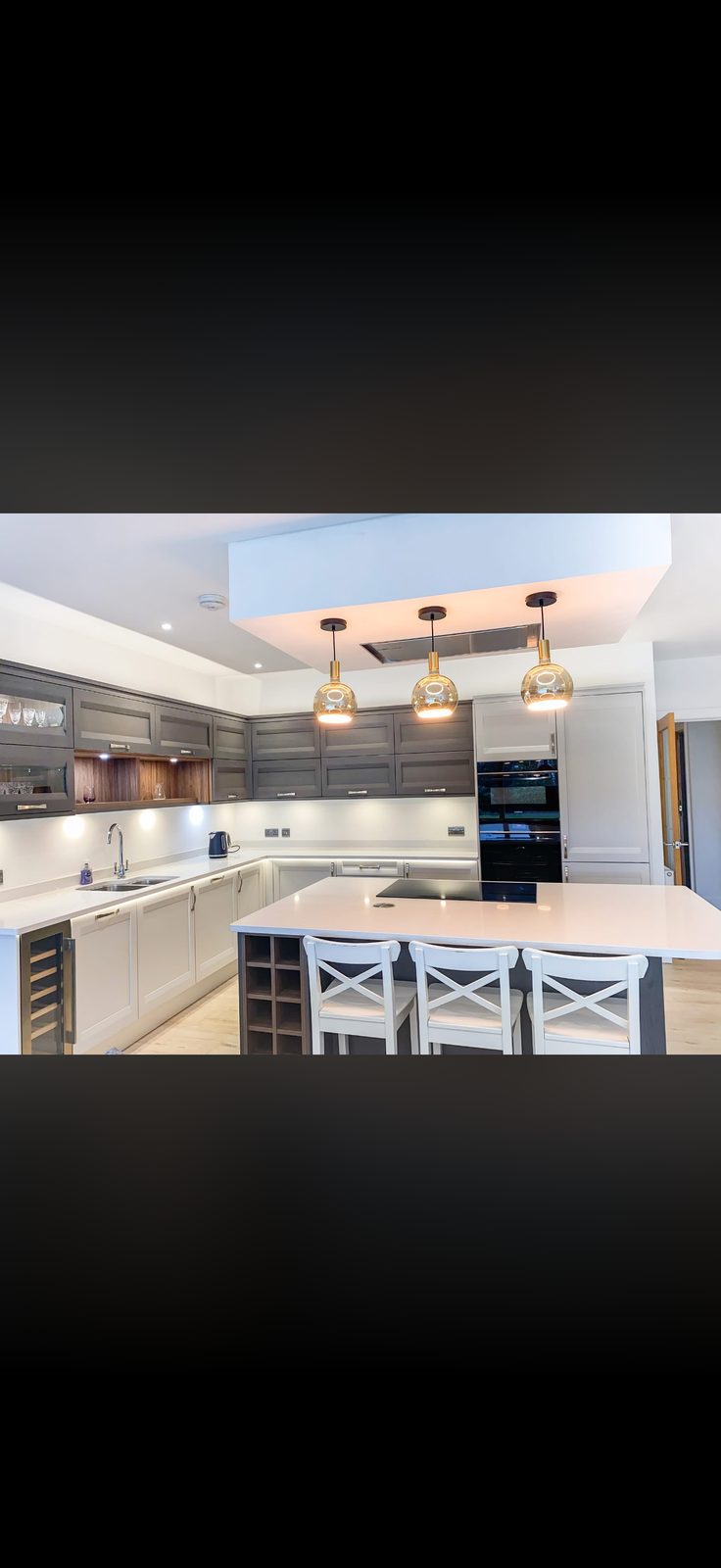 Open-plan kitchen with island cooktop, oak accents and tall oven housing