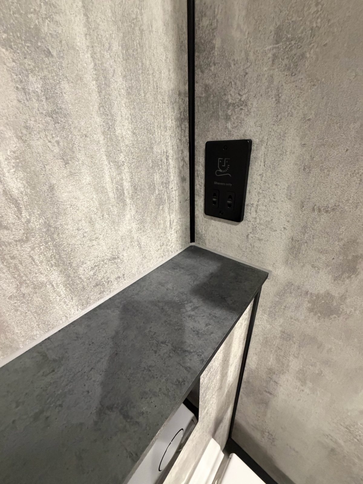 Close-up of matte black shaver socket on grey wet room wall panels