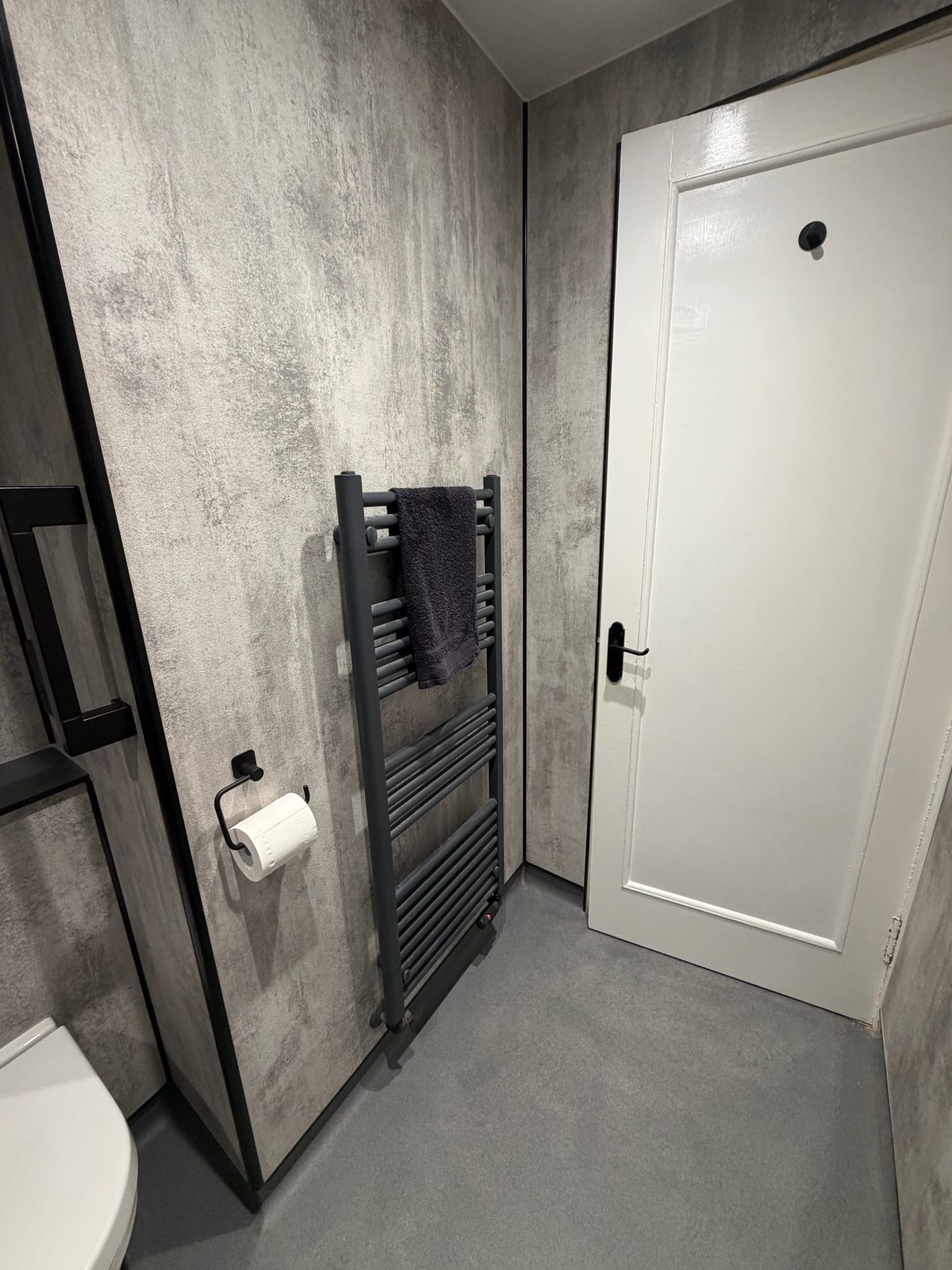 Wet room WC with matte black towel rail and towel beside door